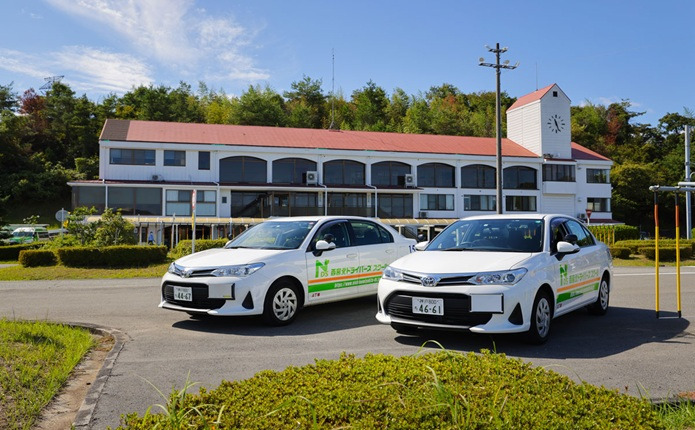 校舎をバックに教習車